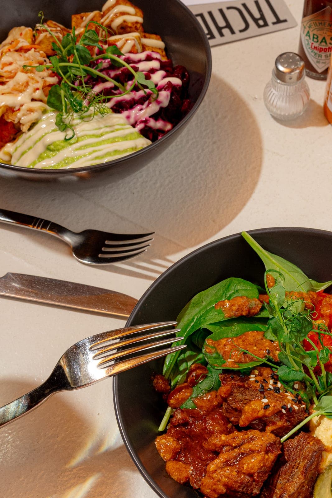 Zwei Bowls mit Spinat, Beef und Dressings